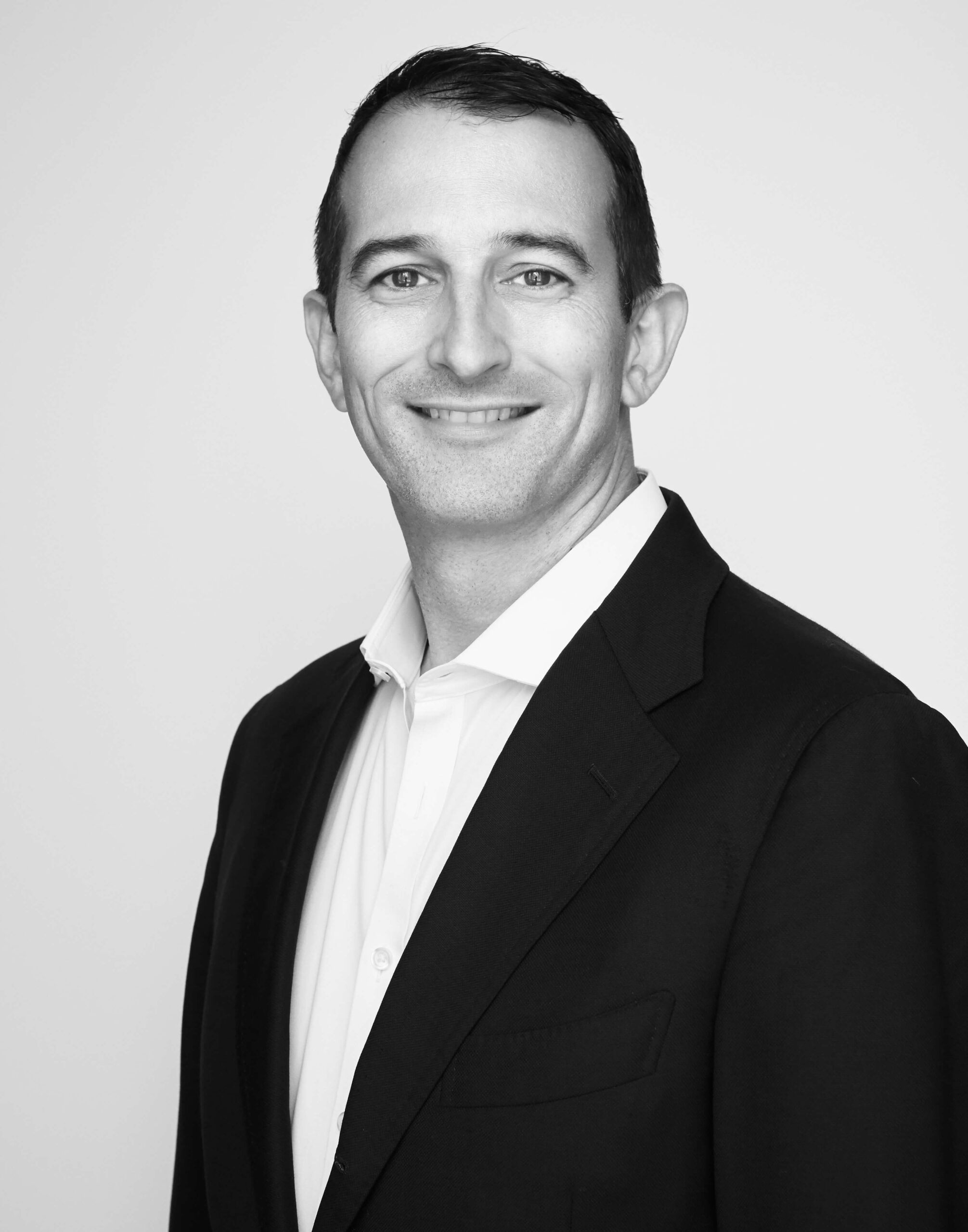 Man in suit smiling, monochrome portrait.